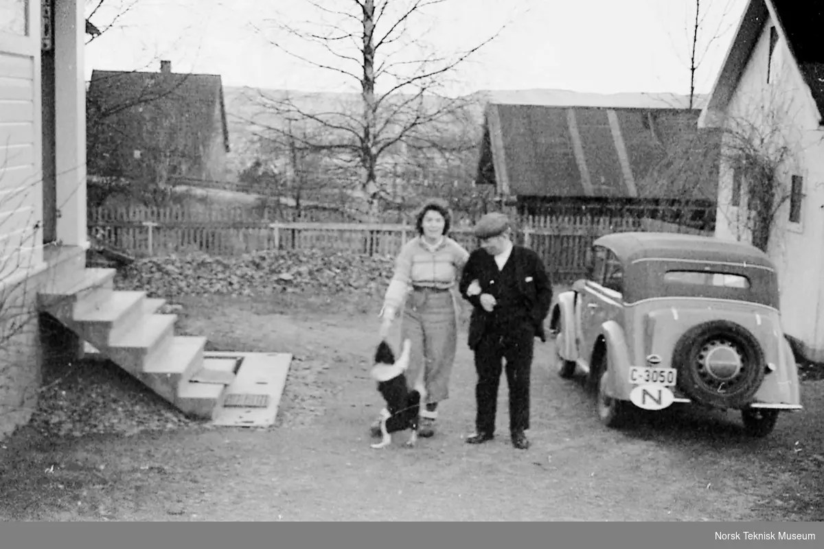 Hans Halvorsen og svigerdatteren Annie med hund ved bilen i Hasleveien utenfor Halvorsens Verksted, våren 1940