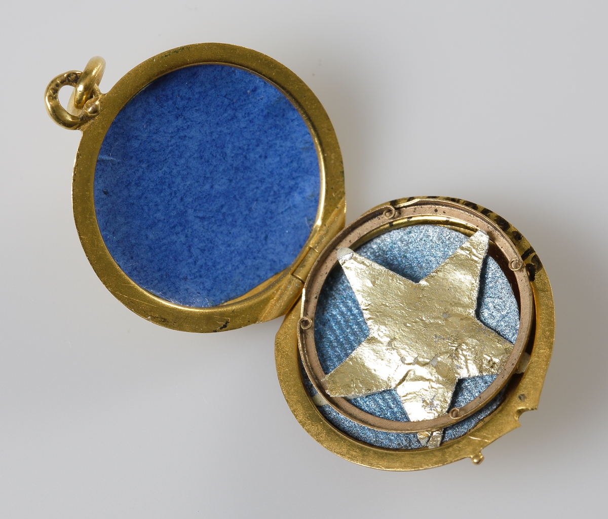 Öppningsbar berlock i 24K guld, med en infäst pärla på locket. Inne i berlocken en pappersguldstjärna.