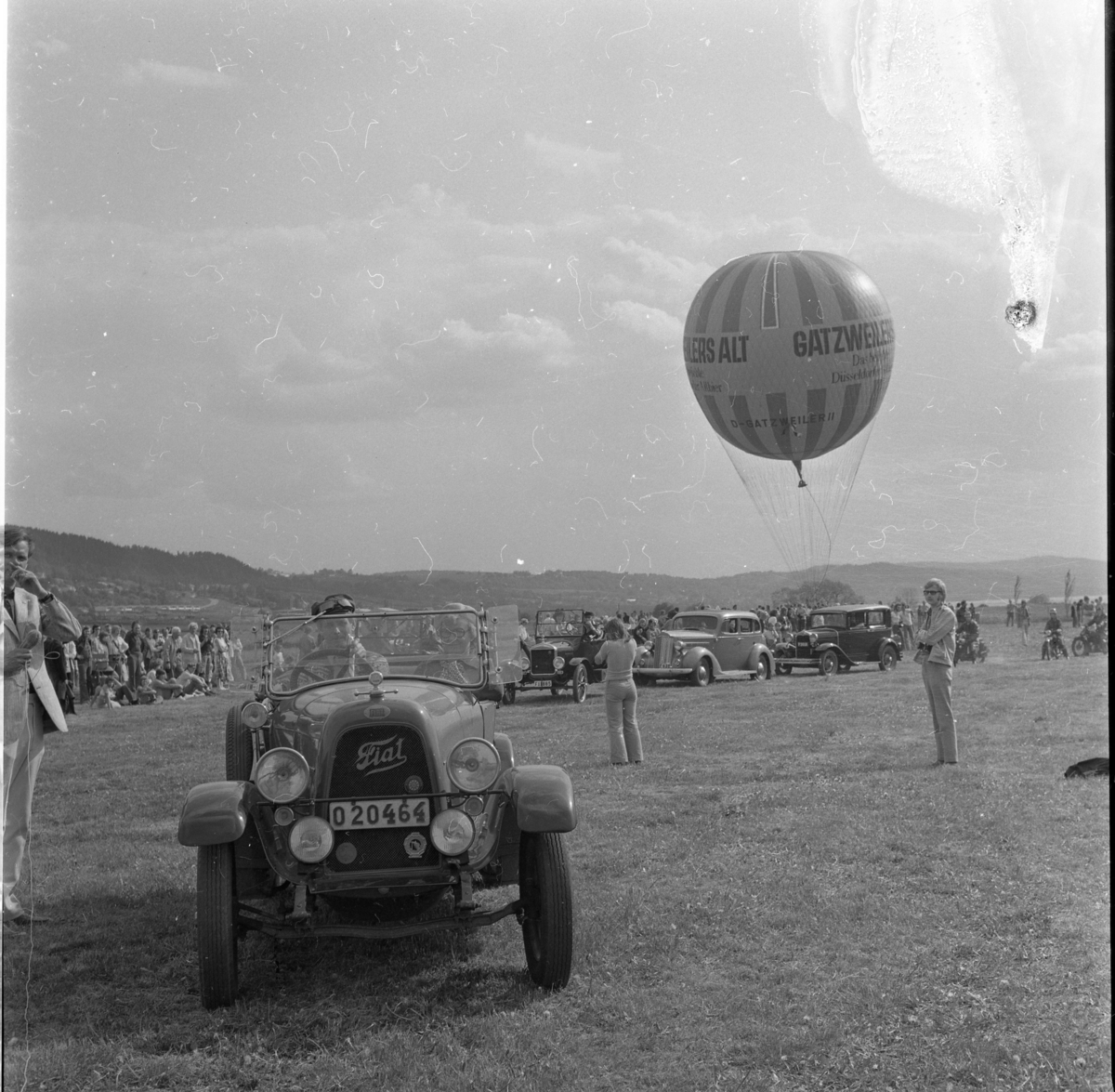 En västtysk gasballong märkt Gatzweilers Alt står beredd att lyfta. Hitom den ett led med veteranbilar, närmast en Fiat cabriolet med registreringsskylt O20464.