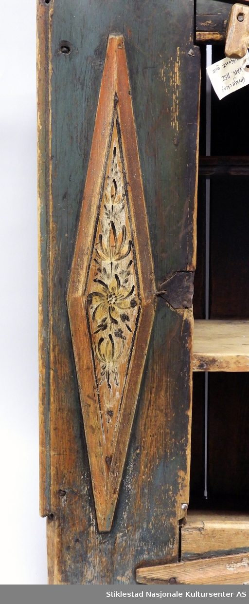 Hengeskapet dekorert med rose- og figurmaling av «rokokkomaleren» Ole Haldosen Berg (1747-1828). Skapet er i bondestil med ei dør i front. Malte speiltfelt. Skapet har liggende profiler i forskjøvet rektangel, disse er dekorert med malt blomsterdekor (hevet over skapets overflate). Over og under dør er profilene montert horisontale, vertikale på høyre og venstre side av dør. Speilfeltet på dør er dekorert med figurmaling, mann og dame i rokokkoklær. Over døra er det montert en vrider i tre, dette for å holde døra lukket. Døra har originale hengsler, nøkkelbeslag mangler, løs låskasse. Grunnfargen er blå. Innvendig har skapet to hyller. 
Gesimsen øverst på sideveggene er fjernet, og spikrene på hengslene er skiftet ut, ellers er skapet intakt med originale beslag (festet på nytt?).