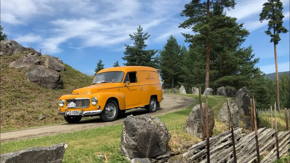 En gul volvo duett kjørende i museumsparken.