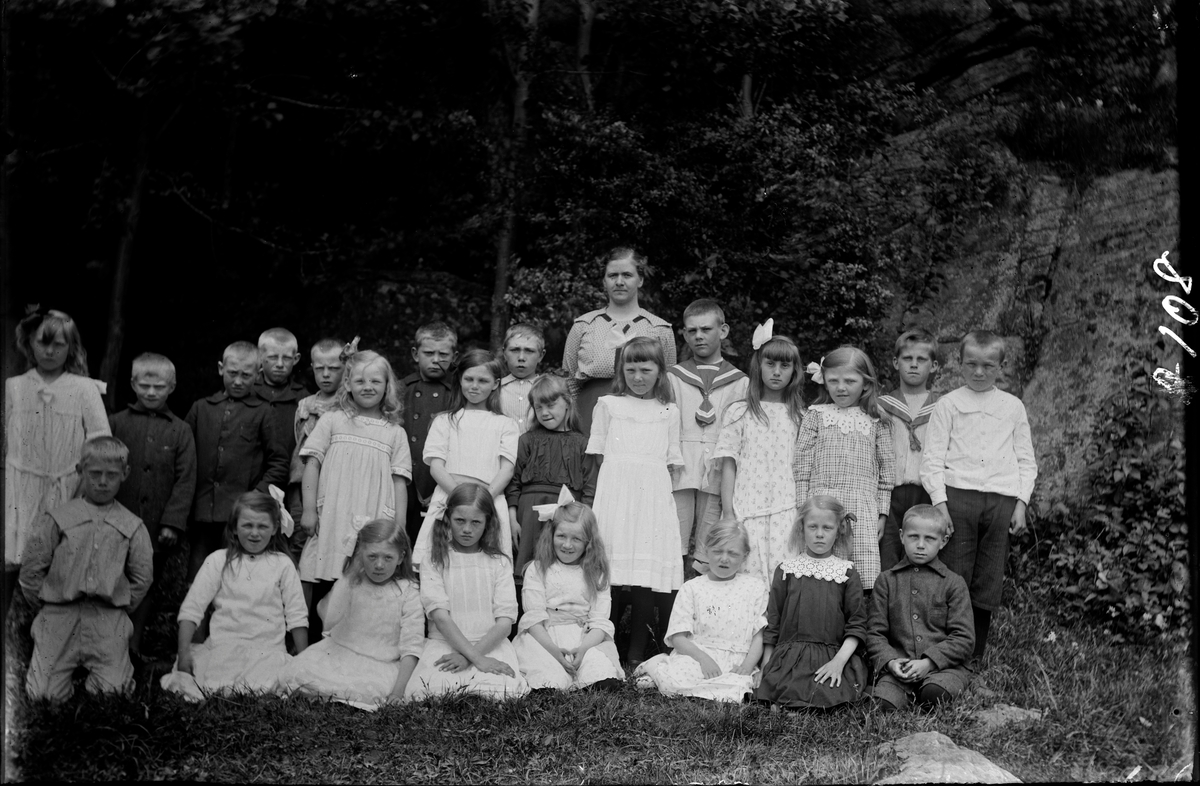 Två versioner av skolfoto från Syllinge småskola i Veddige där lärarinnan Signe Conradsson står i bakre raden. Många av flickorna har rosett i håret.