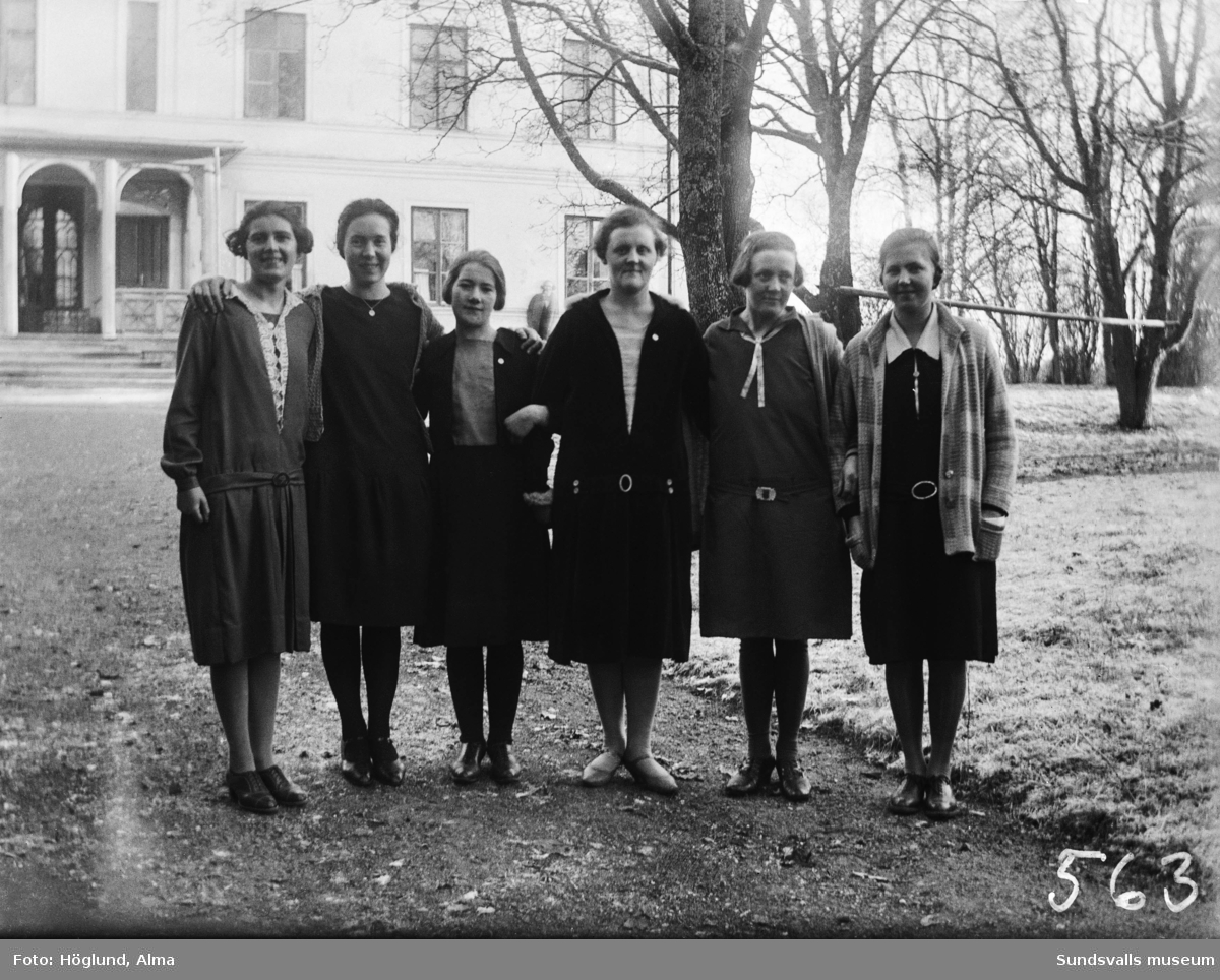 Gruppbild med fem unga kvinnor samt en lite äldre (lärarinna?). Troligen ett skolfoto, i bakgrunden syns Hussborgs herrgård. Andra kvinnan från vänster är Hilma Höglund, Stöde.