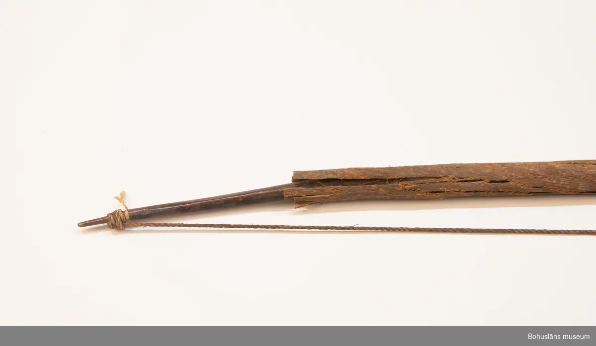 Ur handskrivna katalogen 1957-1958:
Praktbåge, Afrika
L. 137 cm; mkt hårt trä; bågens mittparti är klätt m. skinn, som skyddas av ett barkfodral; sträng av hampa. Hel.

Lappkatalog: 9