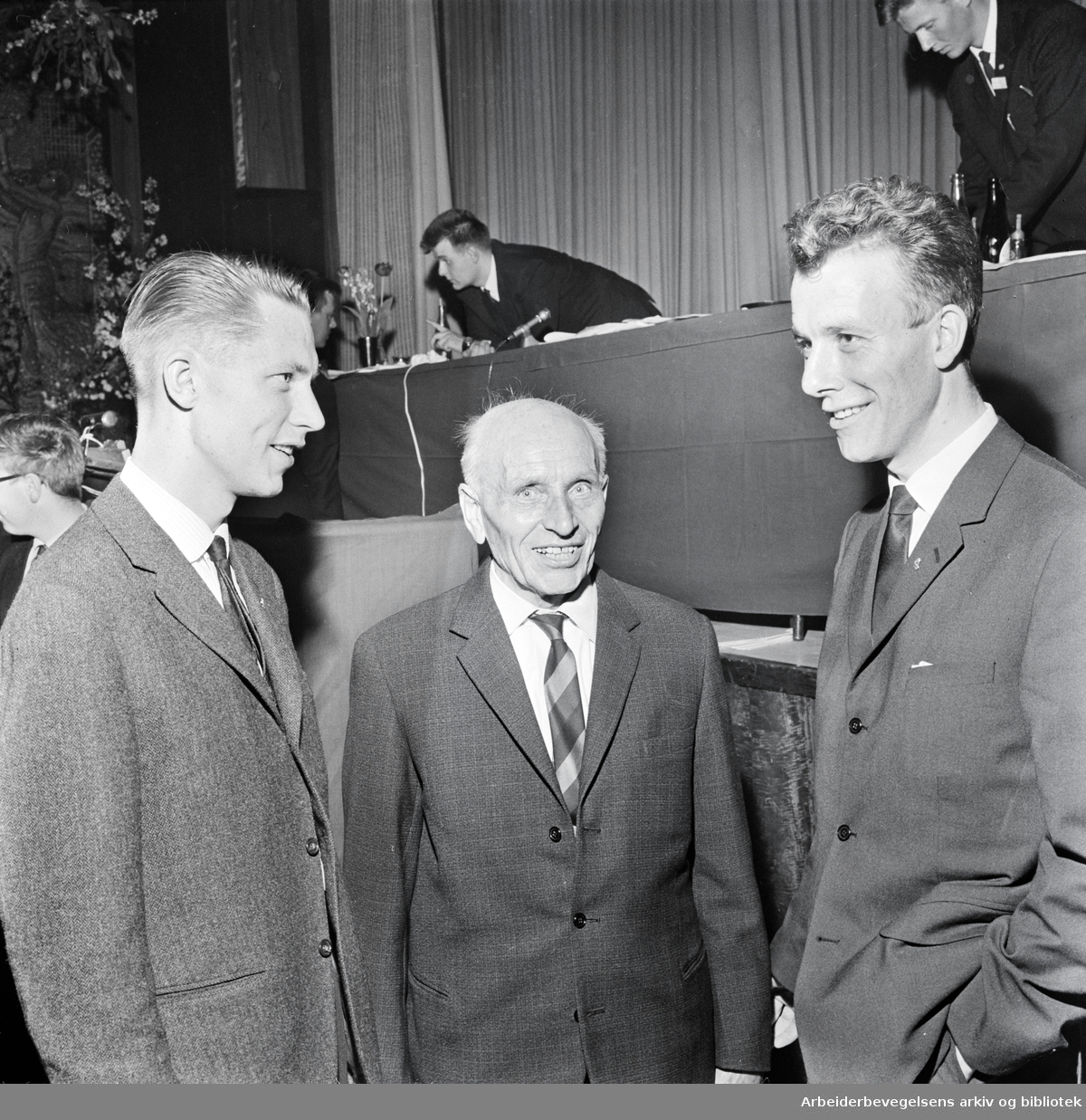 Martin Tranmæl (i midten) med AUFs påtroppende formann Ola Teigen og avtroppende formann Reiulf Steen (til høyre). Samfunnssalen, April 1964