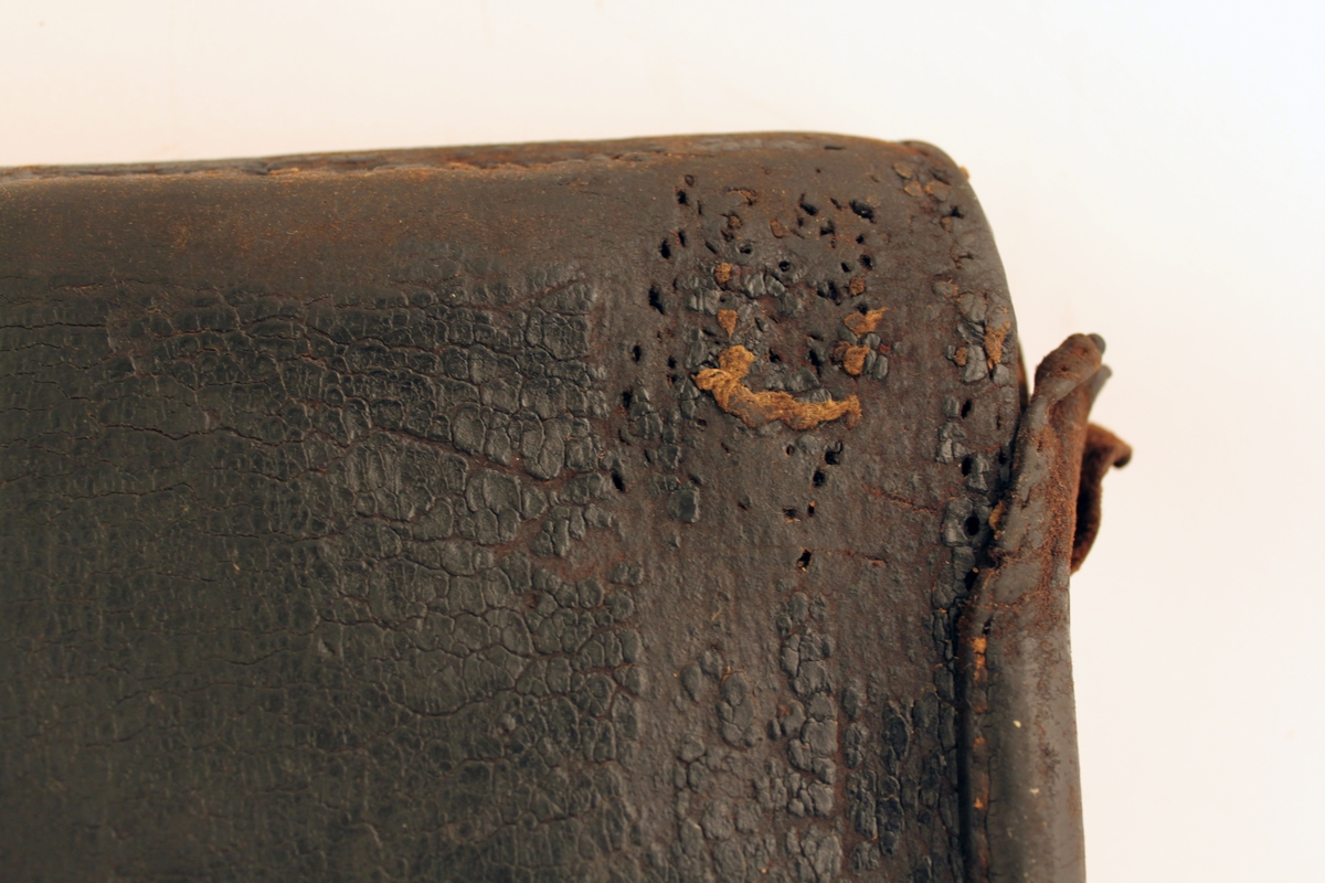 Lösväska av svärtat läder med spännen och låsinrättning. Stor
klaff med sydd inskription: Gyllenfors Qvarsebo.