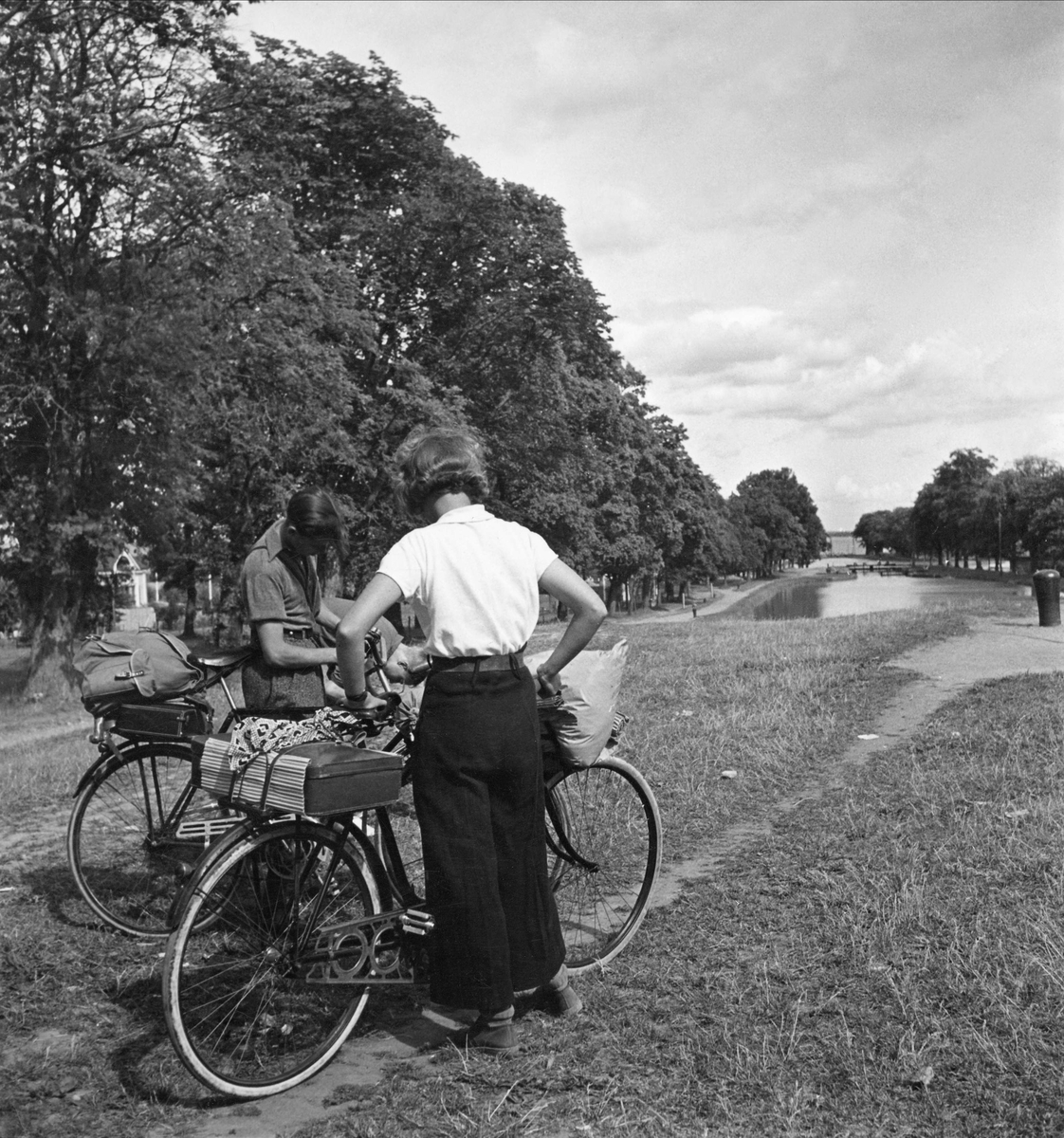 Cyklister, kvinna och man, med packning på pakethållarna står vid Göta kanal.
