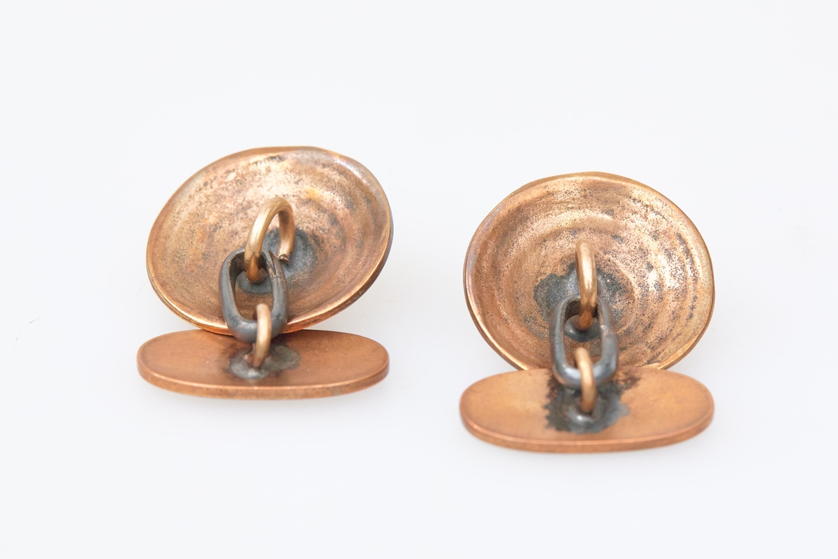 Et par mansjettknapper i bronse med dekor som etterligner totennåla. Brukt med totendrakt.