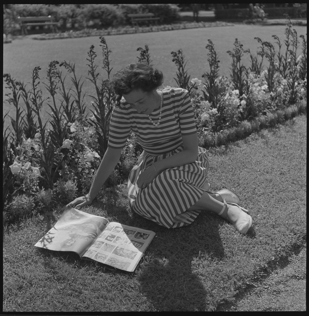 Kerstin Åsén läser en tidning i gräset i Plantaget.