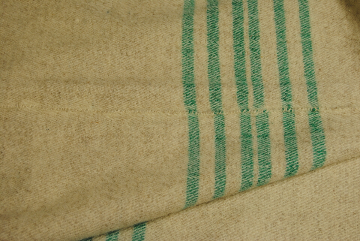 Eit stort kvitel i melert ullstoff med striper i grøn. Sydd saman av to delar. Endane er sydd for hand med tjukk grøn tråd.