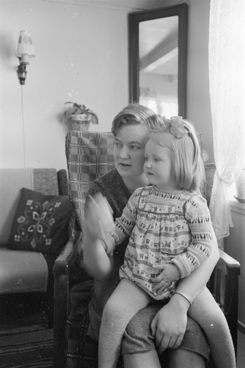 Portrett av en kvinne som sitter i en lenestol på et barn på fanget.
