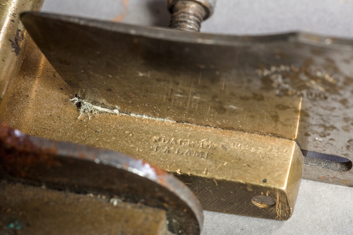 Lærkutter med knivblad i metall og håndtak i tremateriale. Lærkutteren er festet til en skjæreplate med paralellskjærer og linjal opp til 10 cm.