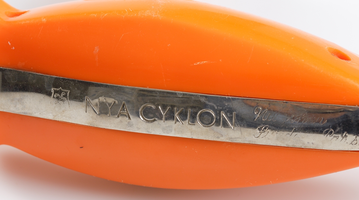 Handvispen "Nya Cyklon" i rostfritt stål av märket Nilsjohan. Vevhandtag och handtag i orange plast. Mekaniken, bestående av ett antal kugghjul i plast, drivs med en vev. Veven kan flyttas mellan två olika uttag, beroende på vilken kraft som önskas få överförd till de båda visparna.