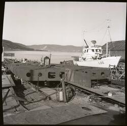 Fotografi av en båt under bygging på et båtbyggeri og et ver