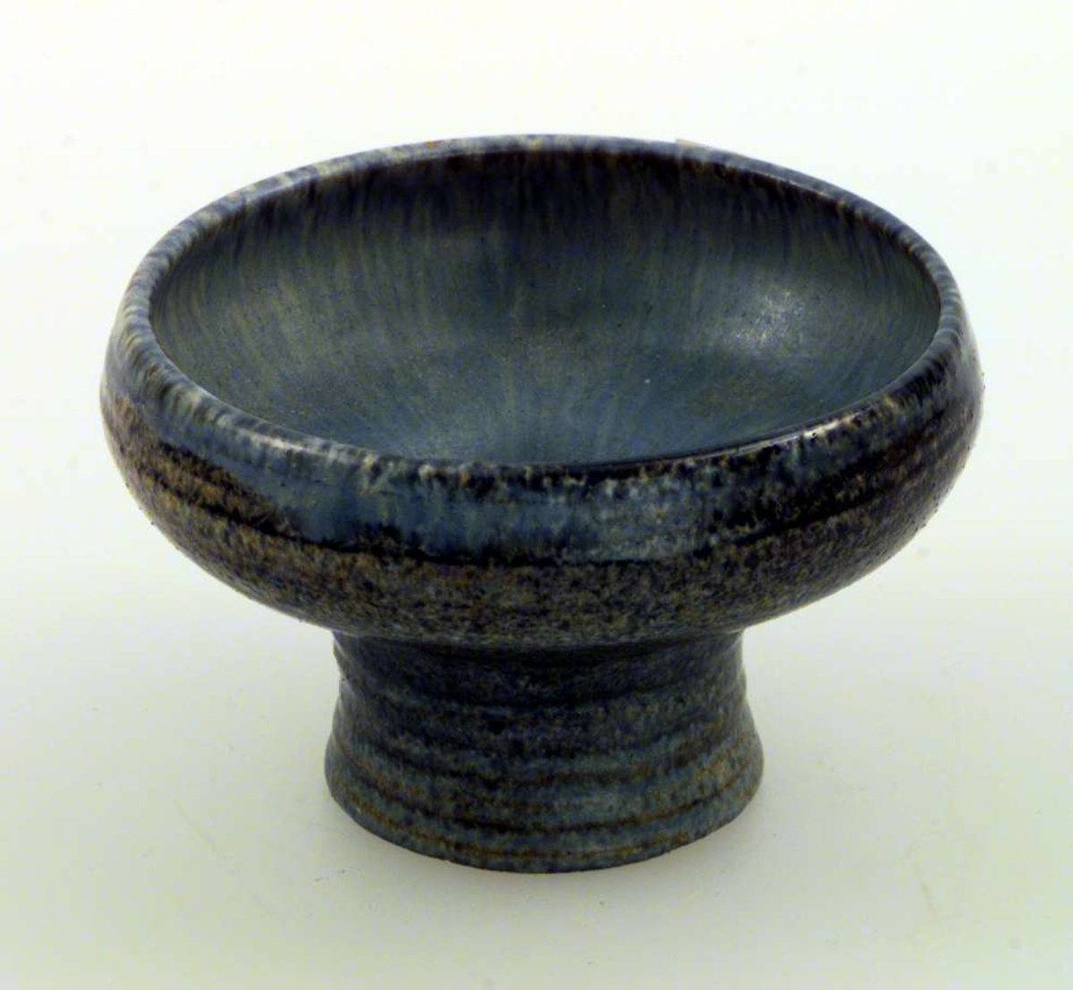Skål med høy fot. Skålen er av keramikk. Den har blågrå glasur.
