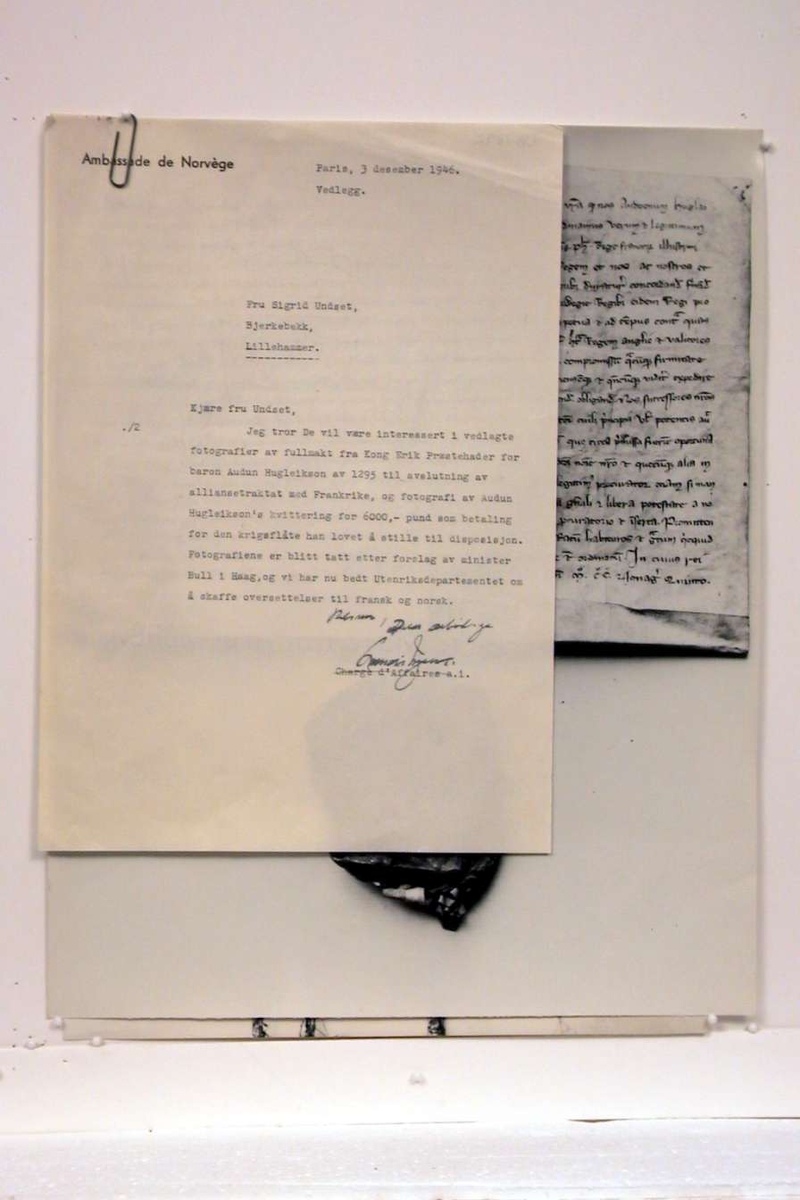 Pappomslag som inneholder 2 sort/hvite fotografier av historiske tekster og et brev.