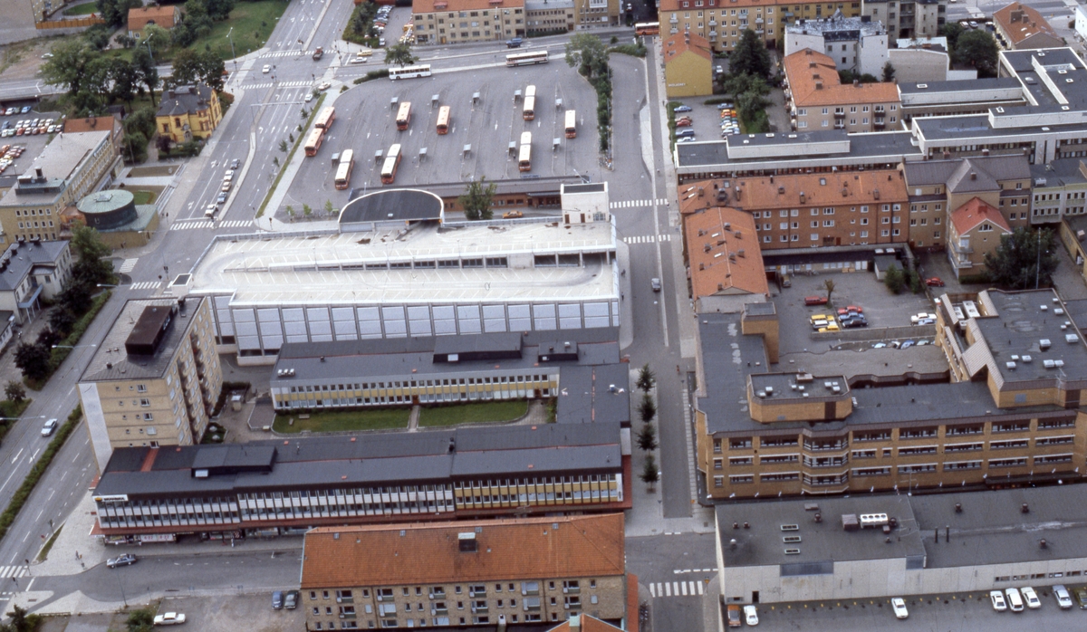 Flygvy över parkeringshuset Druvan och Magasinstorget med Hamngatan till vänster i bild. Centrala Linköping. Busstorget. Bussar. År 1986.