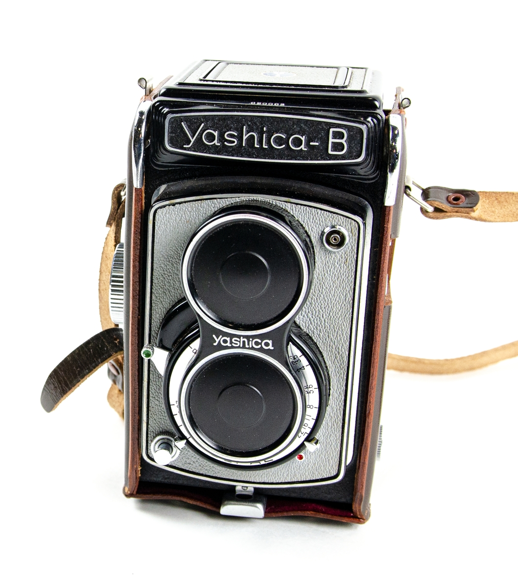 Kamera Yashica, modell B. Monterad i en tillhörande beredskapsväska där alla betjäningsdelar är synliga och lättillgängliga. Väskan är i läderutförande. Förvarad i originalkartong. Tillverkad av Yashima Optical Ind. Co., Ltd., Tokyo, Japan.
