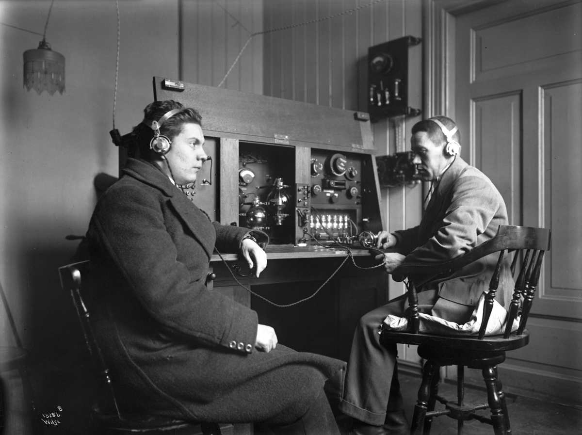 To yngre herrer lytter til radio, antatt yrkesspesialister innenfor telefon og telegraf.