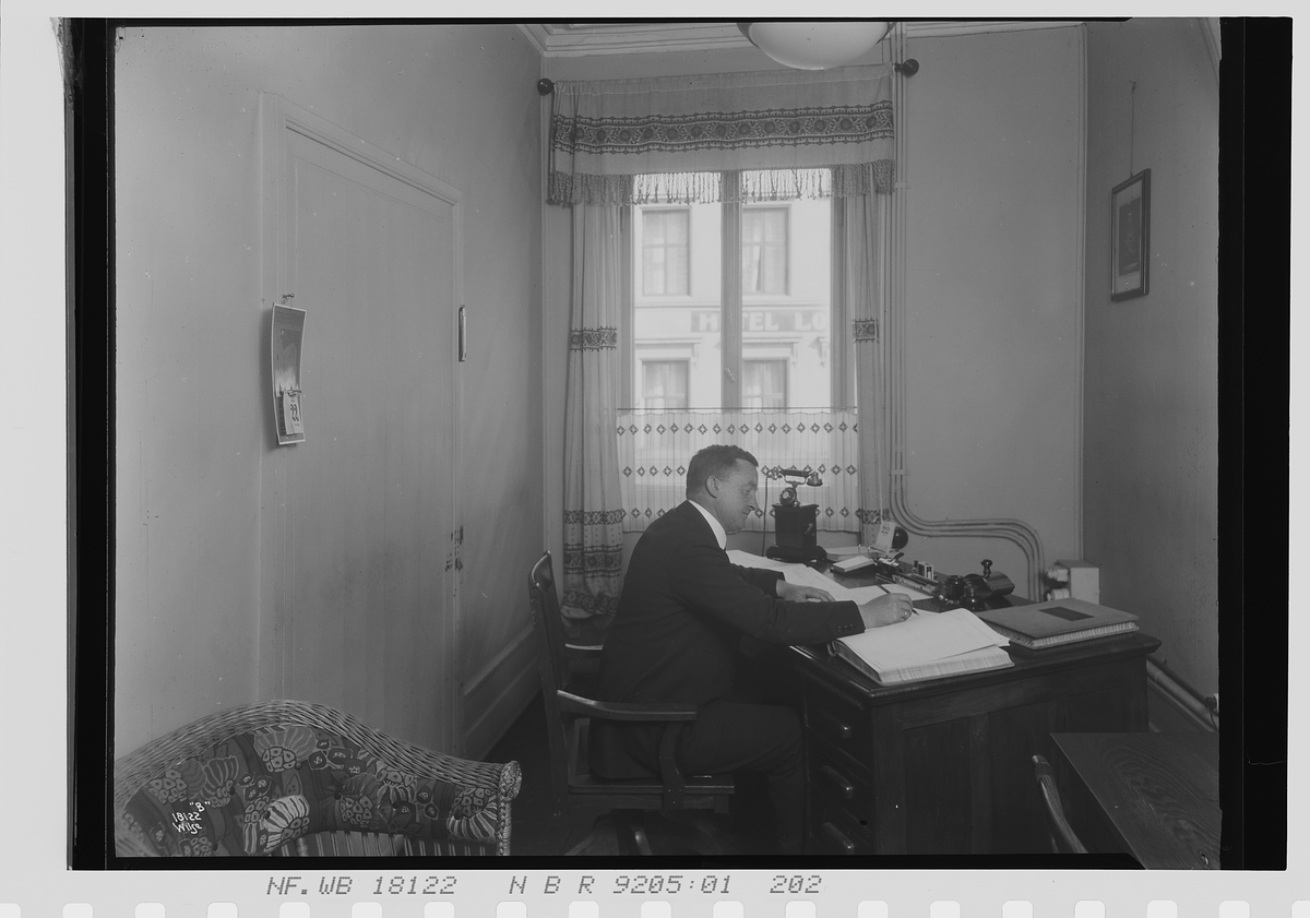 Mann sitter ved kontorpult, Vinmonopolet. Fotografert 1924.