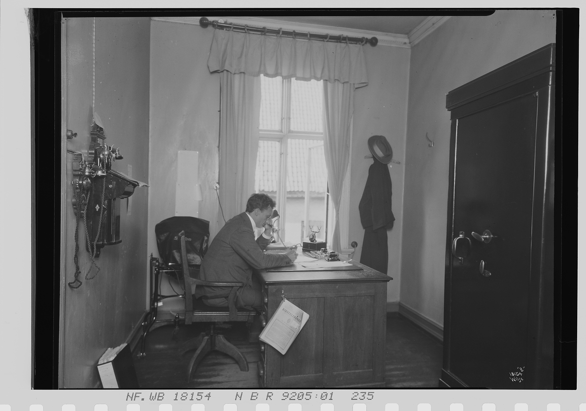 Mann sitter på et kontor i avd. B, Vinmonopolet. Fotografert 1924.