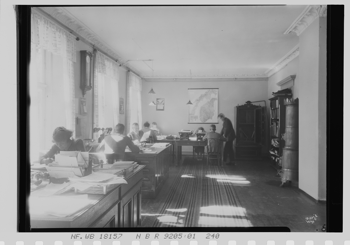 Menn og kvinner sitter sammen i stort kontor i avd. C, Vinmonopolet. Fotografert 1924.