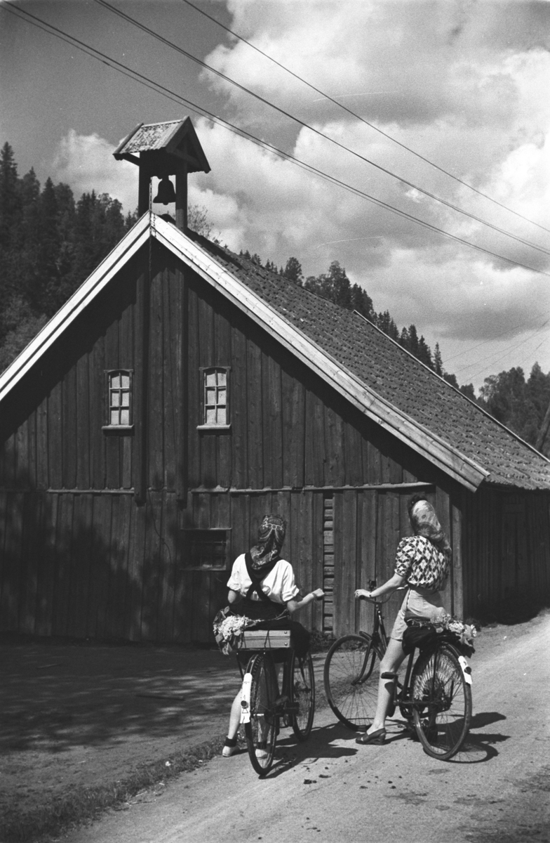 To damer på sykkeltur tar en pause på gårdstunet.