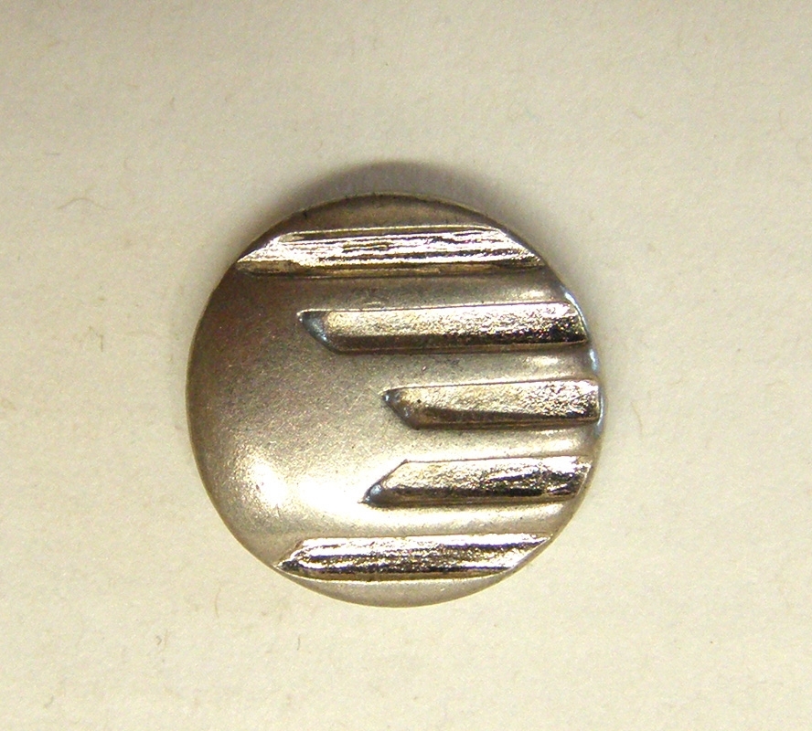 Silverfärgad ärmsprundsknapp med X2000-logotyp.