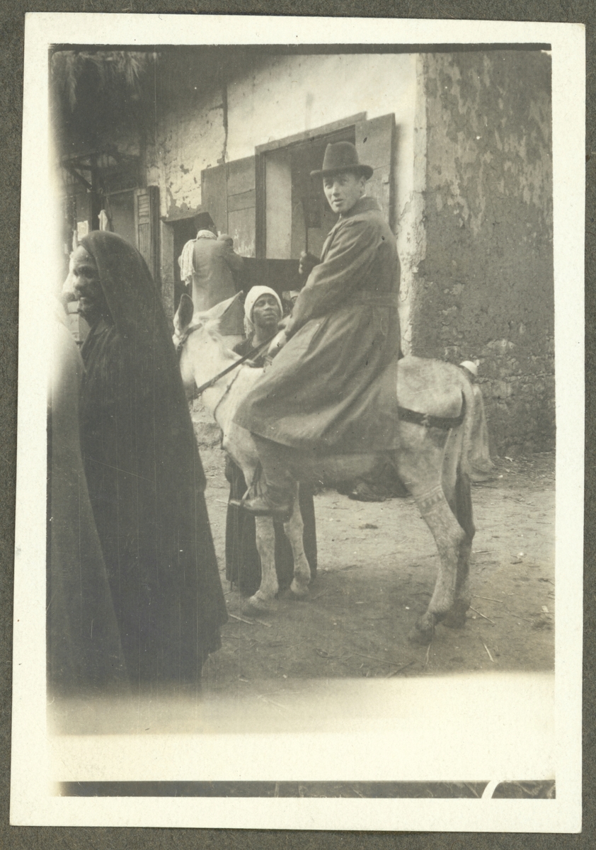 Bilden visar en man i västerländska kläder som sitter på en mula omgiven av egyptier i arabiska kläder.