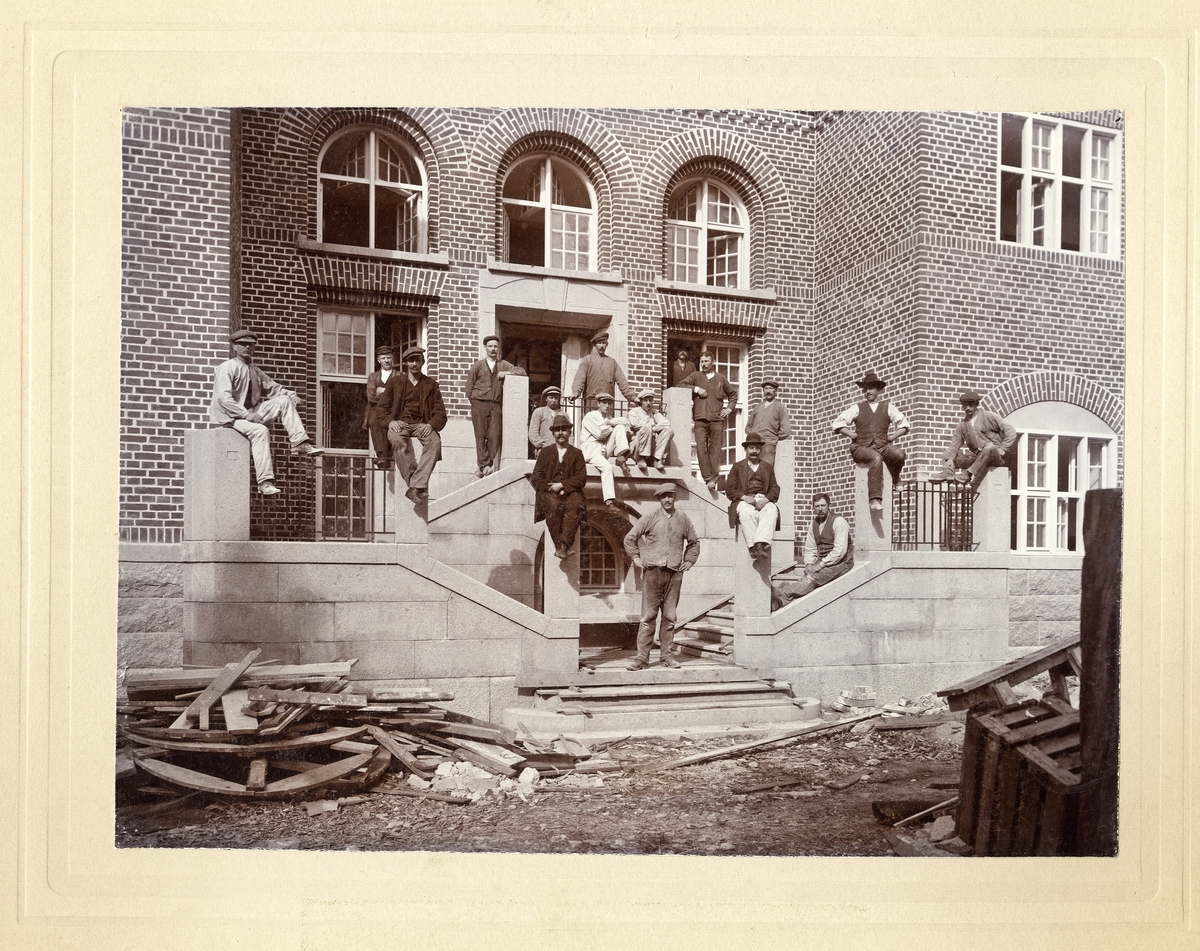 Murare, snickare och målare har samlats utanför entrén till det nybyggda badhuset i Växjö, 1912.