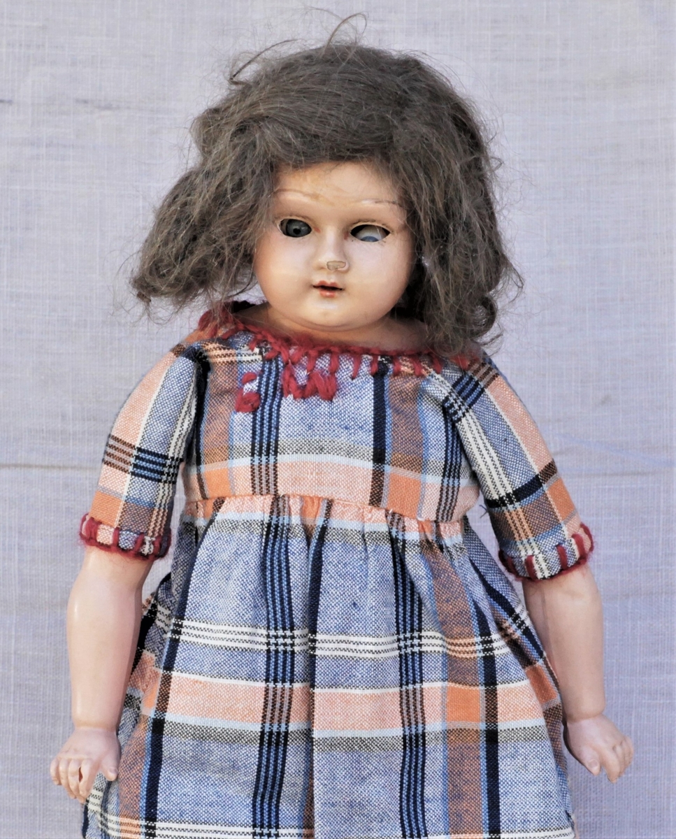 Dukken er en "Skilpaddedukke" med tøykropp, celluloidhode og armer. Modell Grete. Original kjole og klær. Brukt av giveren selv og hennes døtre.