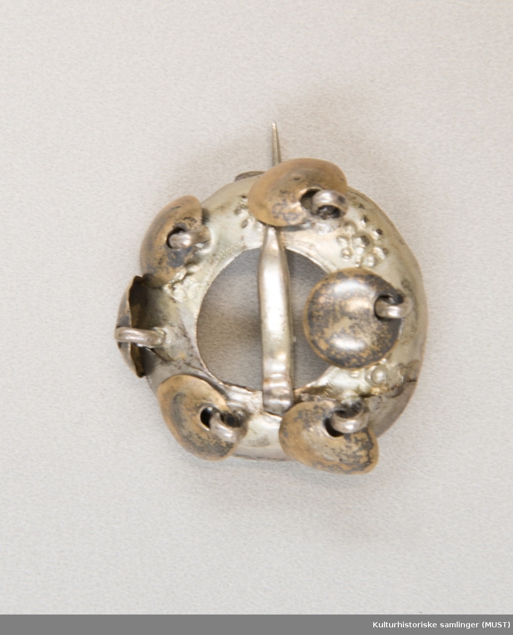Skjoldformet ring med 6 løv. Blomsterlingene dekor mellom løvet. 
Glatt nål. 
På baksiden er den en nål som antas og være sekundær. Bursprettene har opprinnelig ikke nål på baksiden, men på mange spretter er det satt på en mer moderne lukkemekanisme i nyere tid. 