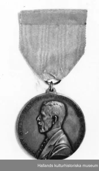 Rund medalj, försilvrad. Diameter 4 cm. Medaljen är fastsatt i ett blått sidenband. Framsida: Gustav V i profil samt text: "GUSTAV V SVERIGES HANTVERKSORGANISATIONS BESKYDDARE". Baksida: Kvinna knytande en krans, sittande på en tron. En sköld med tre kronor samt text: "TILL YRKENAS FÖRKOFRAN OSCAR DAHLBERG 1939". En säkerhetsnål fastsydd på sidenbandets baksida.