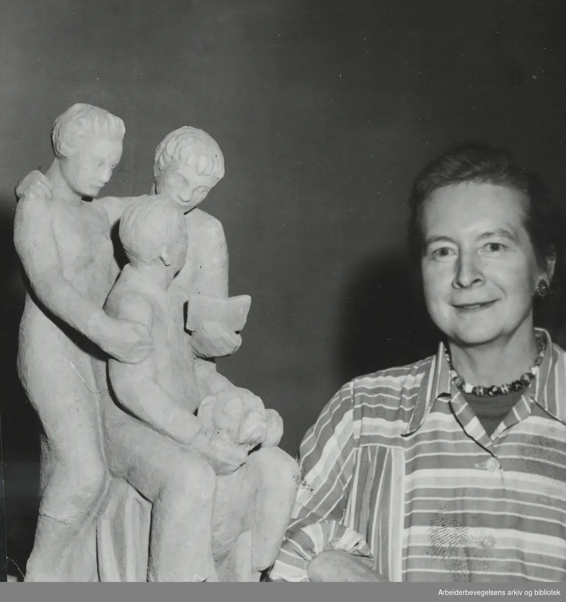 Billedhuggeren Maja Refsum, egentlig Thea Marie Refsum (1897 - 1986) med skulpturgruppen "Min familie" i Kunstnerforbundet, April 1954. Arbeidermagasinet/Magasinet for Alle