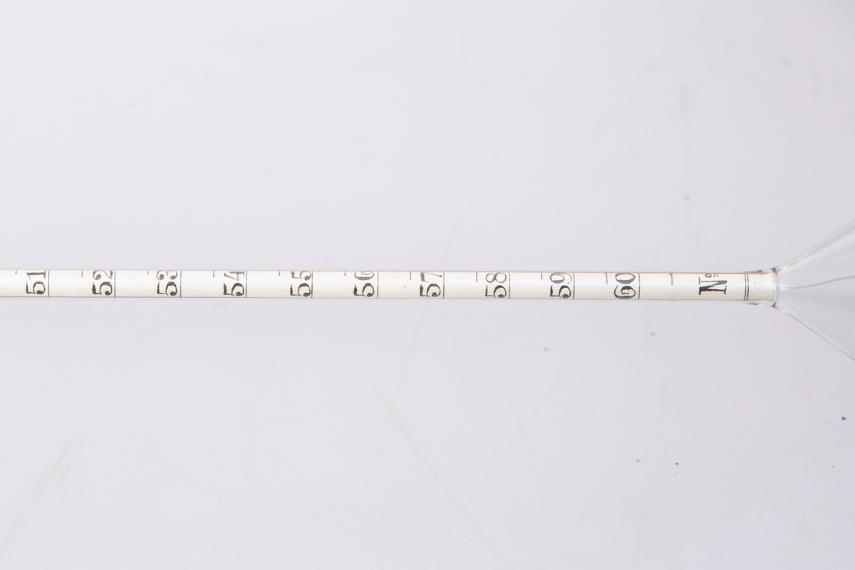 Lactodensimeter (a) oppbevart i en tilpasset eske av papp (b og c). Inne i røret ligger en lapp med følgende påskrift: "Lactodensimeter Temp 15 C oben ablesen". 