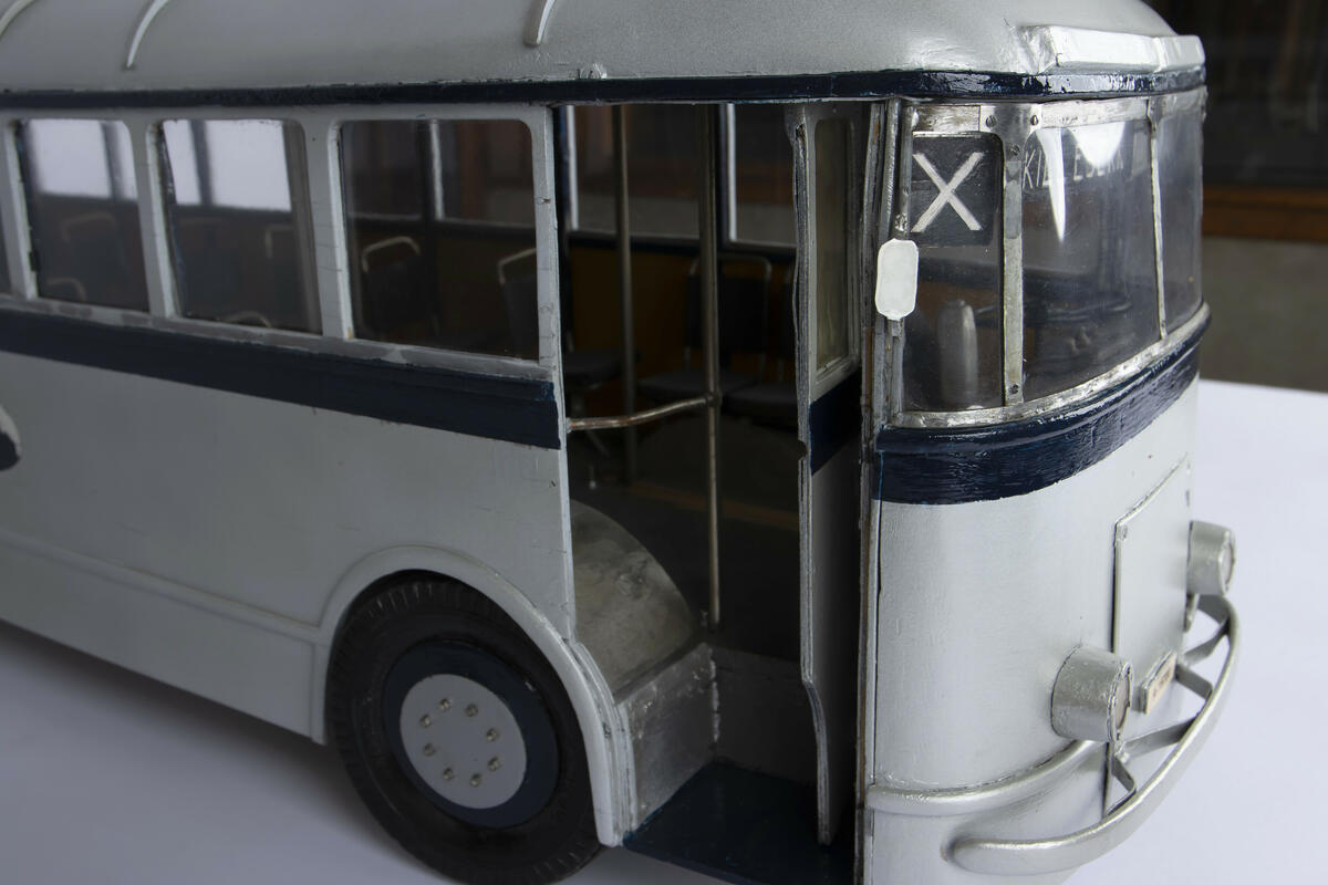 Tremodell av trolleybuss A-15700 med fungerende hjul og inngangs- og utgangsdører. Modellen er farget sølv med en mørk blå stripe som går rundt hele modellen langs midten, samt andre dekorative elementer. Modellen har to fungerendee fjærbelastede trolleystenger/strømavtagere på taket og kroker som stengene kan hektes på på bakre del av taket til bruk hvis bussen må taues. Interiøret består av okergule vegger og enkeltseter i en brun farge.