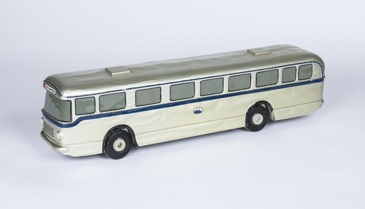 Tremodell av sølvfarget buss med mørk blå stripe som går rundt hele bussen på midten. Over frontruten står nummeret 29 og destinasjon, som er Kampen. 