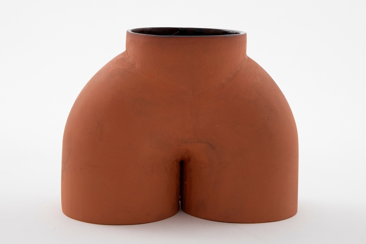 Matt brun vase i terrakotta. Lav voluminøs bueform med en kort sylinder oppå. Mørk brunglasert på innsiden.