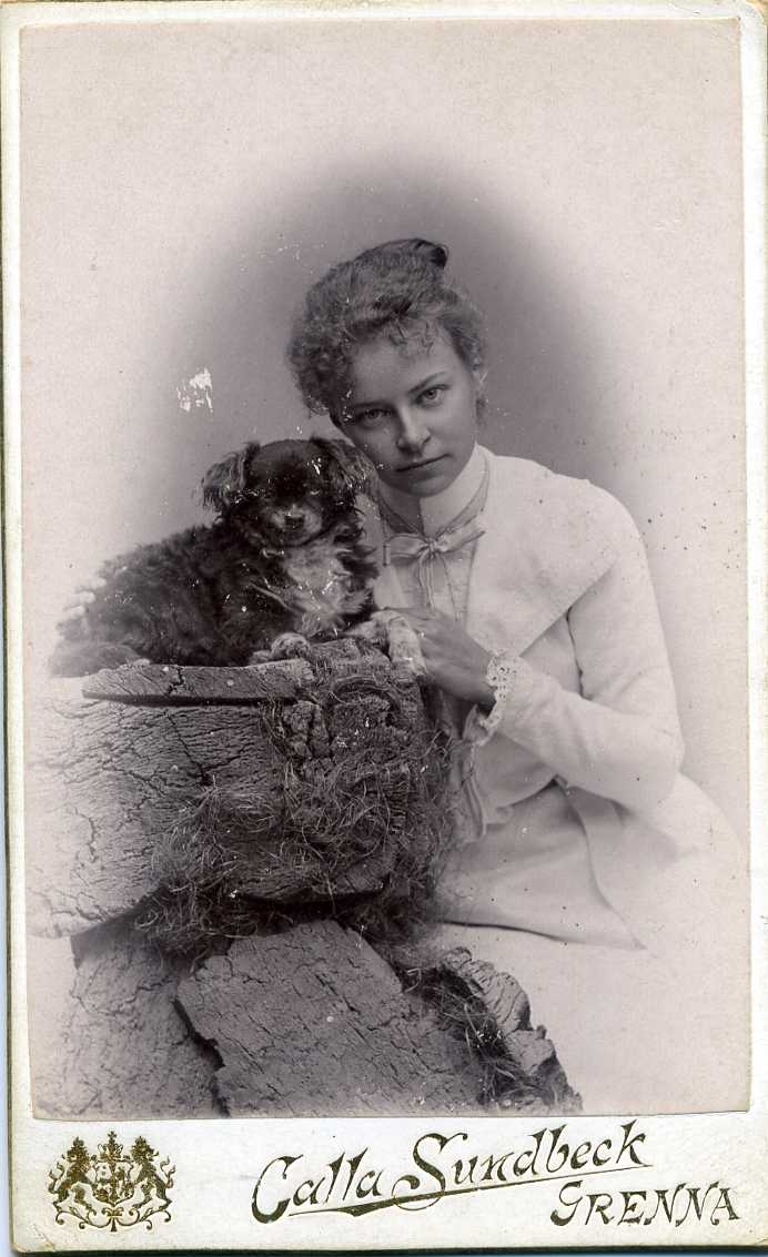 Porträtt av en ung kvinna som sitter tätt intill en hund.