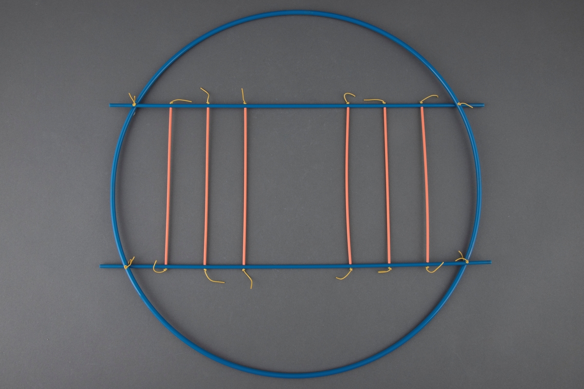 Halssmykke satt sammen av en sirkel av blå plastrør og en "stige" festet på tvers av denne. "Stigen" består av blå plastrør på hver side og seks tversgående "trinn" av oransje plastrør. Disse er festet med tynne, gule plastledninger. Ledningene er knyttet i endene.