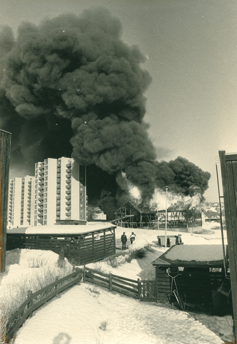 Tre bilder som viser en brann i noe som kan ligne en låve e.l. i nørheten av boligblokker. Bygningen er totalskadd. Snø. Røyk.