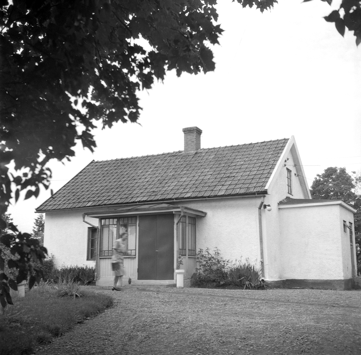 Marstad Löneboställe i Bjälbo, här dokumenterad av Östergötlands museum 1951. Bostadshuset uppfördes ursprungligen av pastoratet och tillbyggdes 1926. Från 1935, och ännu vid tiden för bilden, arrenderades hemmanet av Karl August och Karin Karlsson, sannolikt är det Karin vi ser skynda över grusgången.