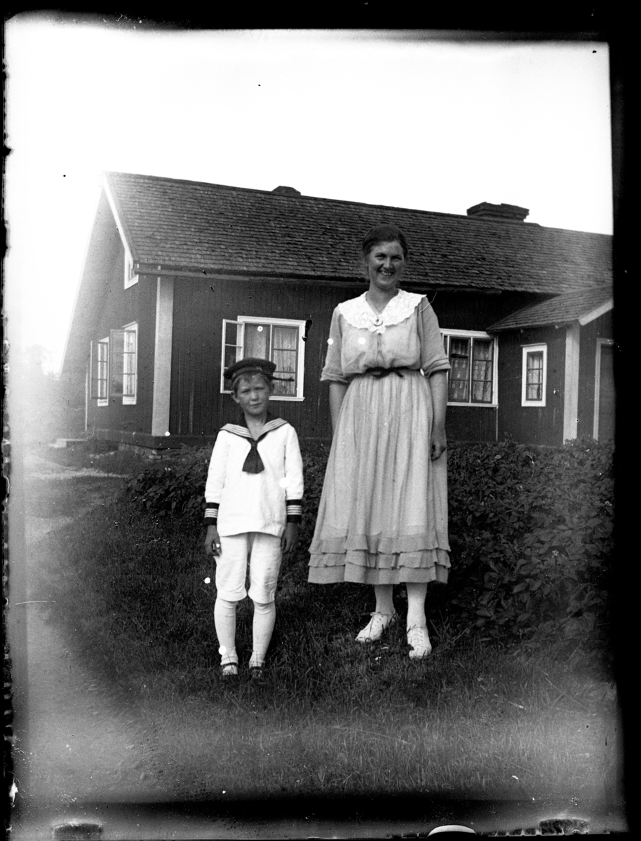 En kvinna och en pojke framför ett hus som sannolikt idag (2023) är Limö Café.
