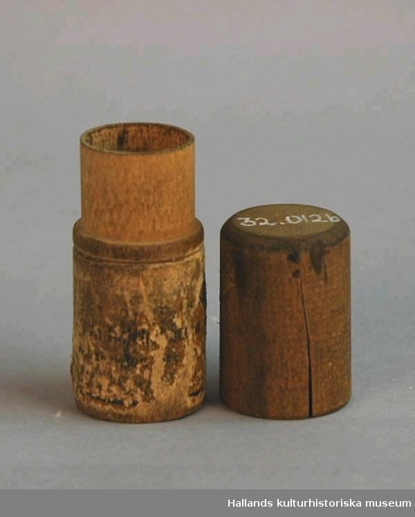Svarvad ask av trä. a) Botten. Längd 45 cm. Diameter 2,2 cm. 
b) Lock. Längd 3 cm. Diameter 2,2 cm.