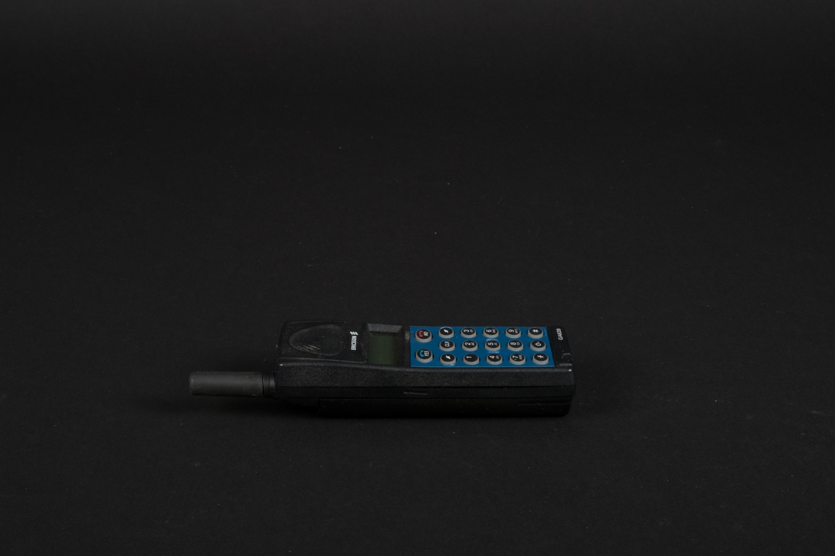 Mobiltelefon i svart plast med löstagbar blå frontpanel. Telefonen har en display och en antenn. Bakstycket utgörs av ett löstagbart batteri. Innanför bakstycket finns en simkortshållare.  Kontakt för laddare finns på telefonens undersida. Bredvid antennen sitter en lysdiod.
