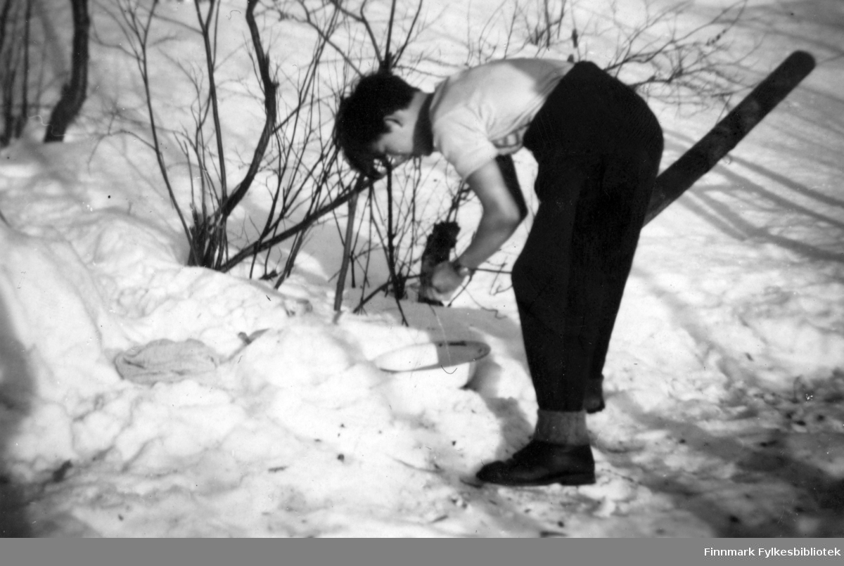 Einar Isaksen som tar morravasken, utenfor gammen i Gokkmokka. Han står bøyd over et vaskefat, som ligger i snøen