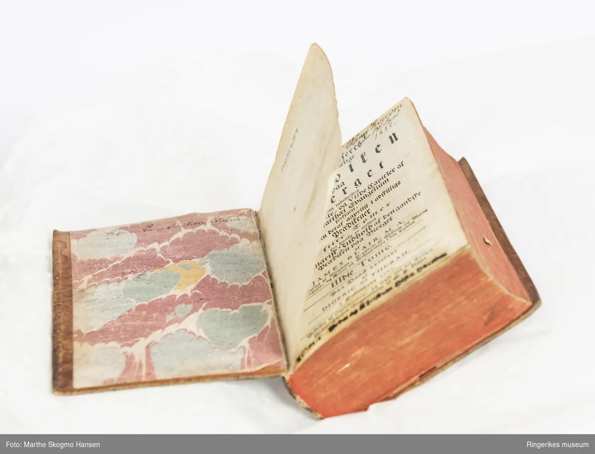 Blairs Bierg Prædiken 1-2. Trykket i København i 1761. 795 sider. Trepermer trukket med lær på utsidene og mønstret papir på innsidene. Sidene er farget røde på yttersidene.