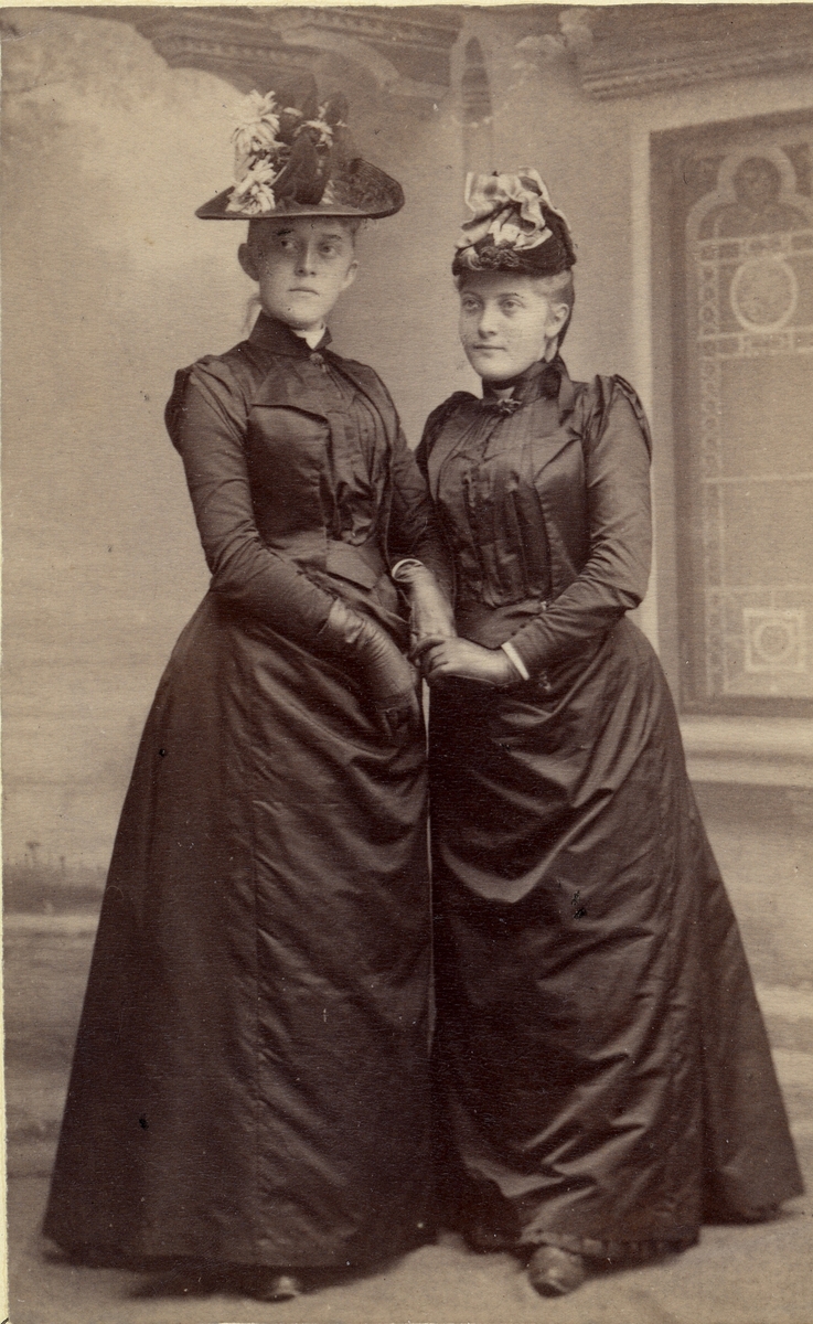 Helportrett. To kvinner i helfigur med kjole og hatt.