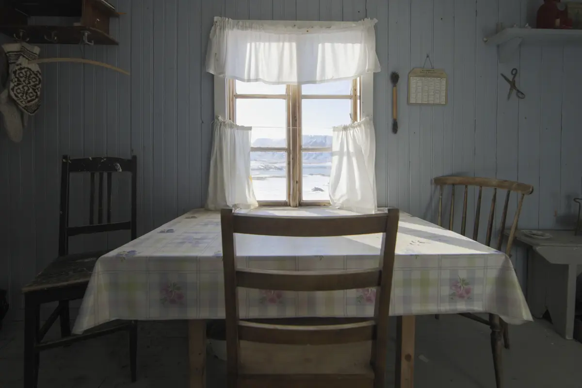 Interiør i Loe-hytta: bord og stol ved vindu.