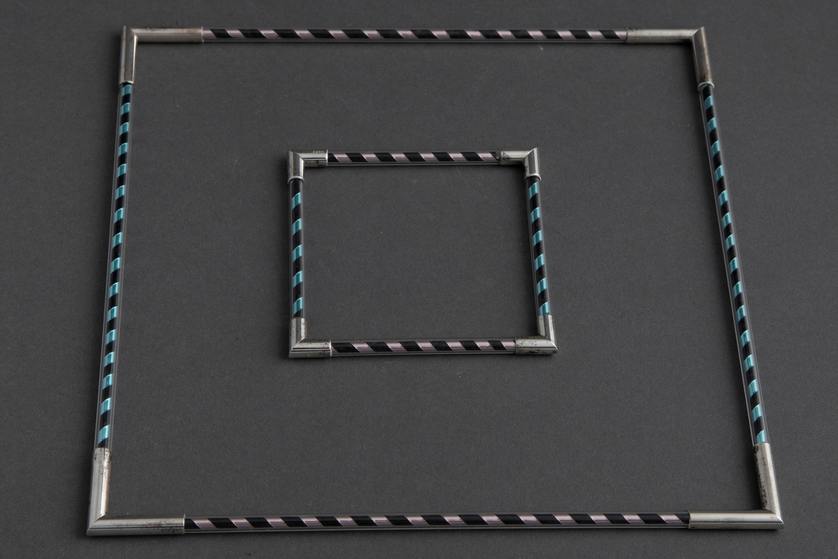 Halssmykke formet som et kvadrat der hver side består av en piperenser surret med metallbånd inni et plexirør. Hver side er knyttet sammen med sølvledd formet som to rør som møtes i rett vinkel. Se NK1985-039 for tilsvarende armsmykke.